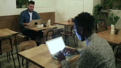 Multiracial-freelancers-working-with-laptops-in-cafe